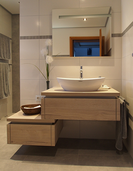 Neuer Waschtisch unter Spiegel bei stimmungsvoller Beleuchtung.